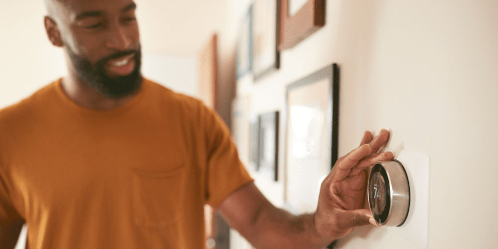 Man adjusting a smart thermostat in his home - Three Reasons to Upgrade to a Smart Thermostat - Allen Heating & Cooling