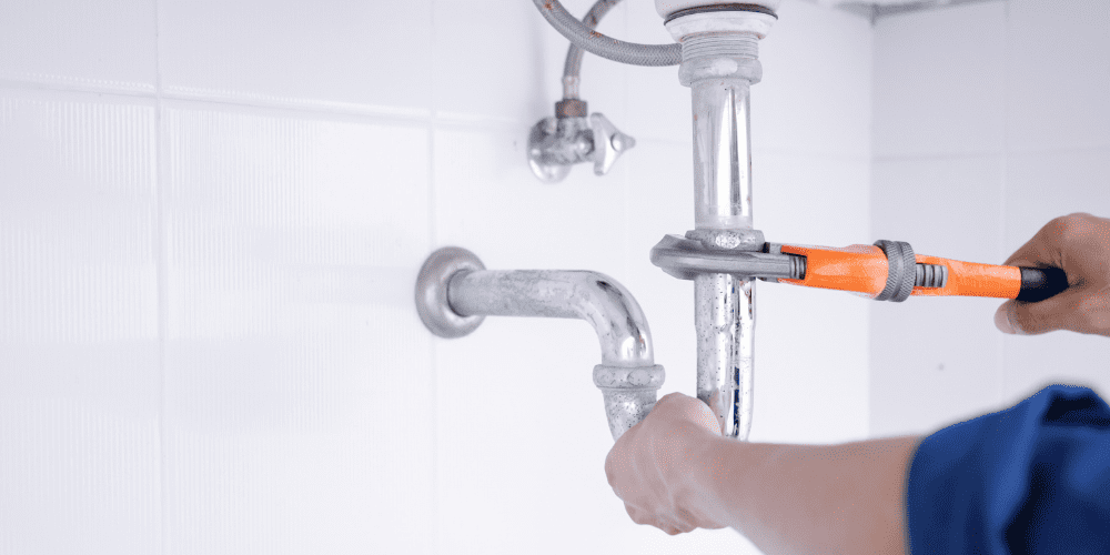Plumber tightening sink pipe - Four Signs It’s Time to Call a Professional Plumber - Allen Heating & Cooling
