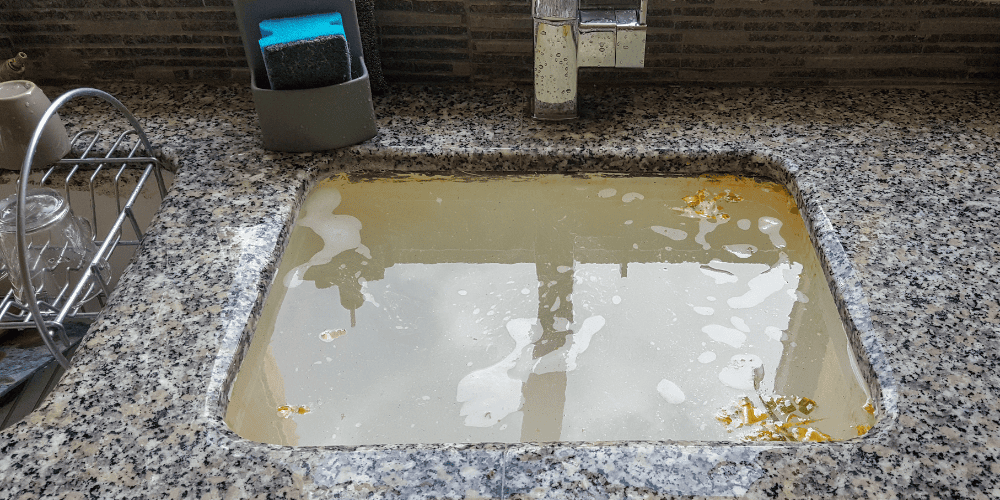 A sink with a clogged drain and filled with backed up sewage - What Causes Clogged Drains & When to Call a Plumber - Allen Heating Cooling and Plumbing